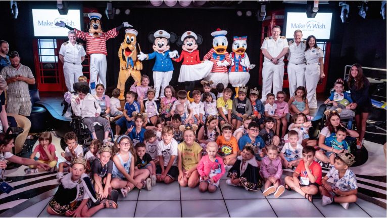 Children posing with Disney characters on stage.