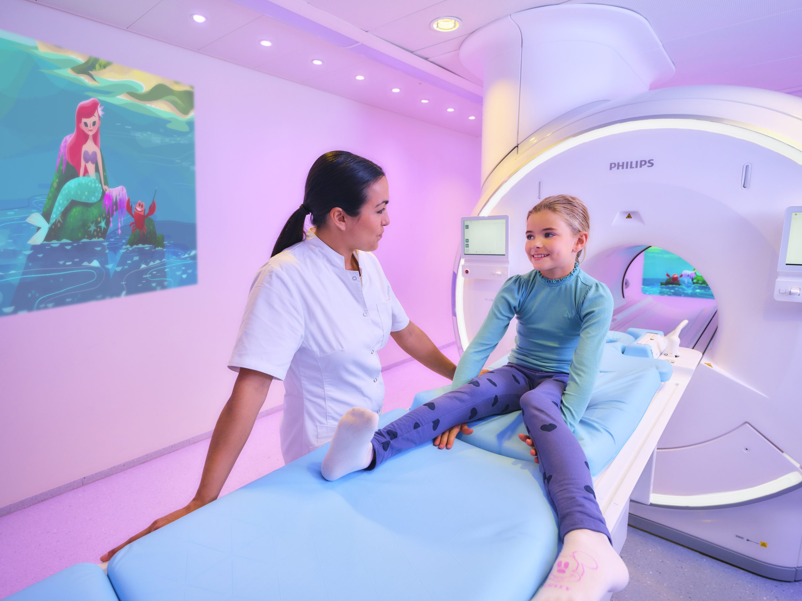 Nurse and patient next to an MRI machine showing the Philips ambient experience for MRIx`